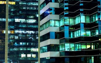 view of glass fronted office buildings at night when lights on