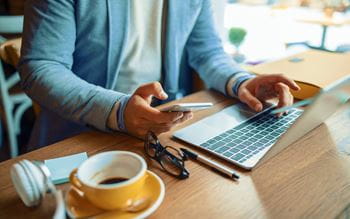 Person with coffee using laptop and phone