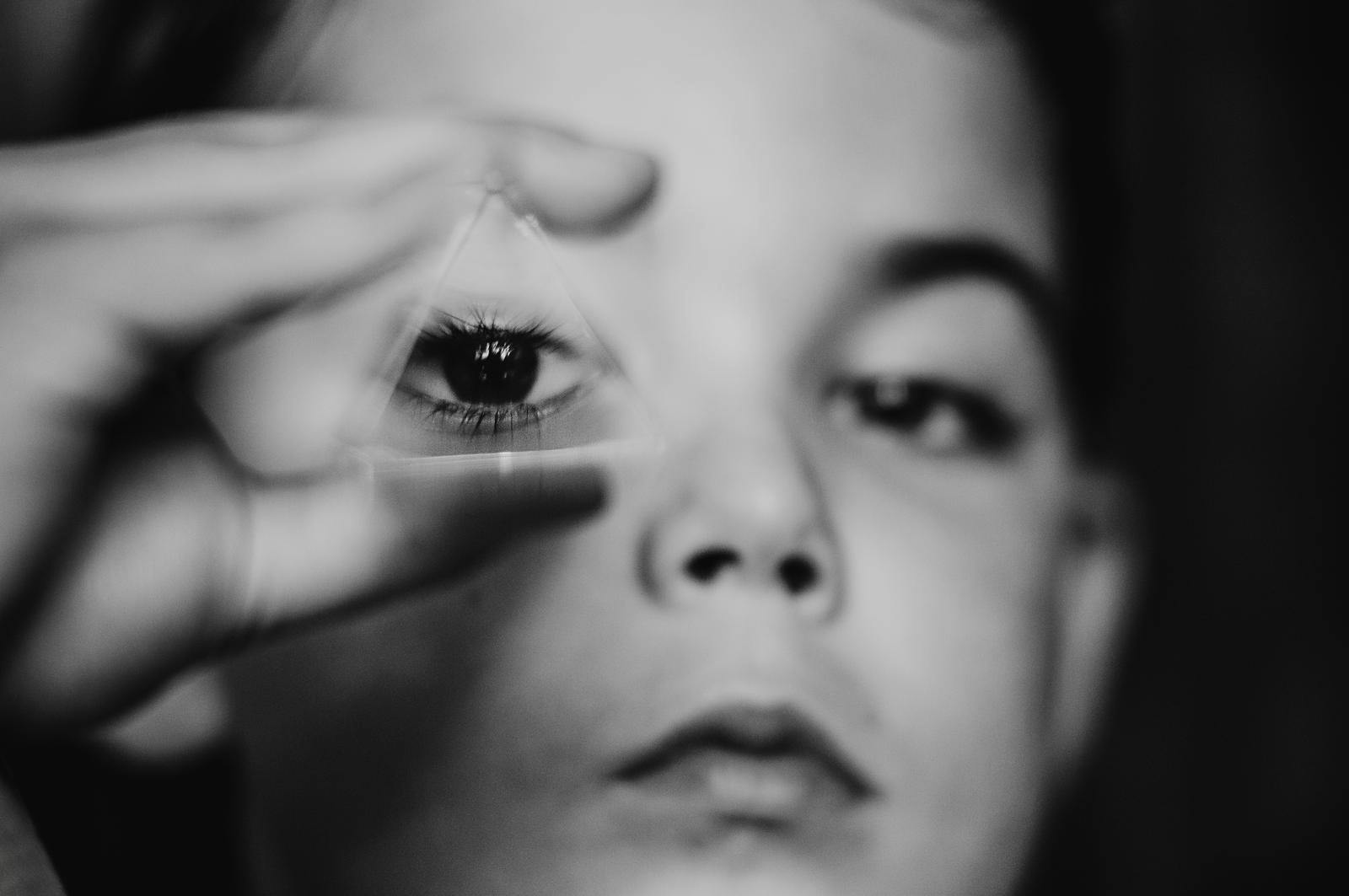 Boy looking through glass prism with one eye.
