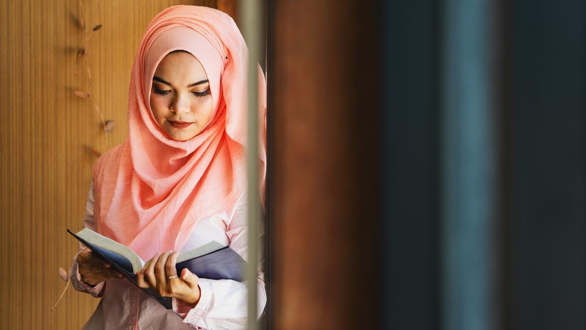 Woman in pink hijab reading a book