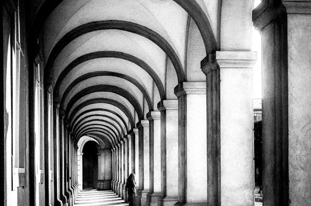 dark hallway with shadows across walkway from tall pillars