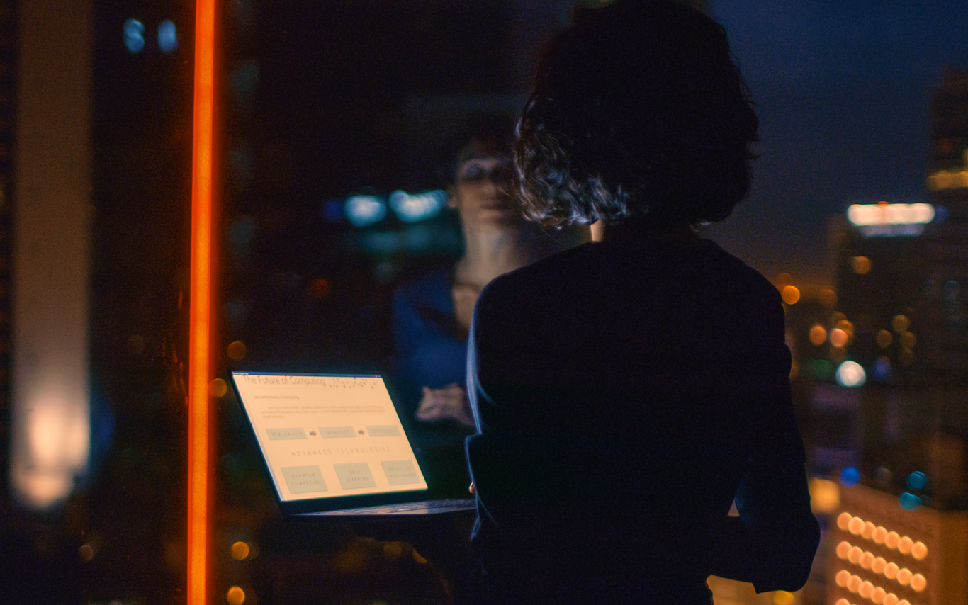 Lady looking through window holding a laptop