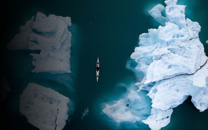 Birdseye view of kayaker sailing through icebergs