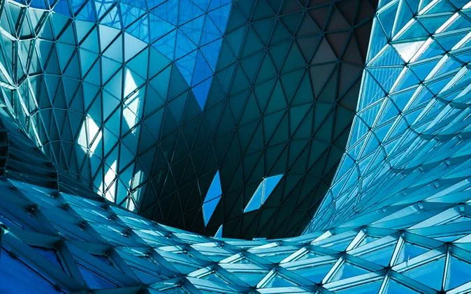 Image of unusually shaped building, glass triangles reflecting blue sky