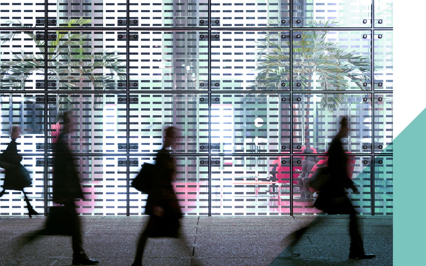 Silhouettes of people walking quickly past a window.