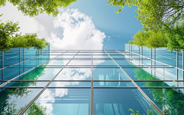 Modern glass building surrounded by green plants and trees 