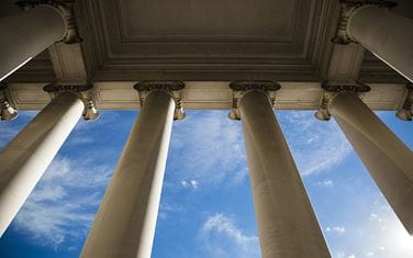Four Grecian columns with a blue sky in the background
