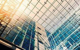 Large glass office building, photograph of glass ceiling with sun shining through. 