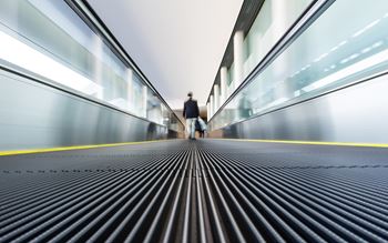 A passenger walking on an airport escalator