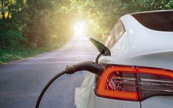 charging electric car on asphalt road in sunset