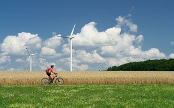A man cycling past wind turbines in the countryside
