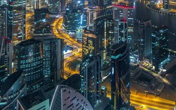 Panoramic aerial view of some illuminated skyscrapers, canal and new towers under construction in Dubai