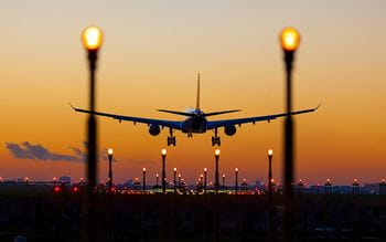A plane landing on a runway a sunrise