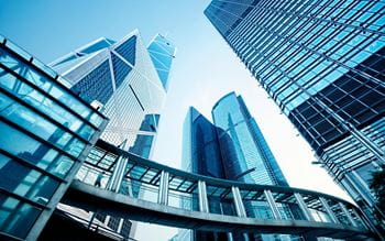 high-rise blue toned steel and glass sky scraper with internal footbridge between buildings
