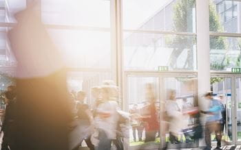 People walking past a large glass window on a sunny day