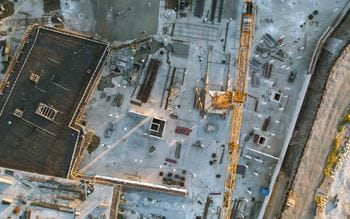Aerial top down shot of a constructions site with team of engineers. Heavy Machinery and Construction Workers.