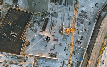 Aerial top down shot of a constructions site with team of engineers. Heavy Machinery and Construction Workers.