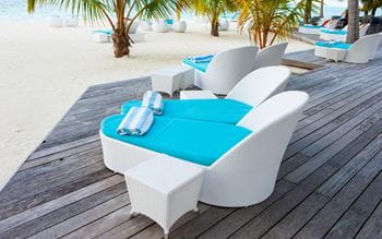 A chair sitting on decking beside a beach. 