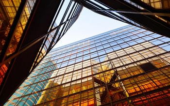 Vertical perspective of buildings with a orange to blue gradient reflection on the glass windows