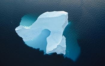 Bird eye view of a iceberg over a sunny blue ocean