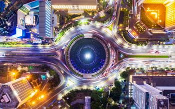 Bird eye view of a city roundabout at night that has four exits