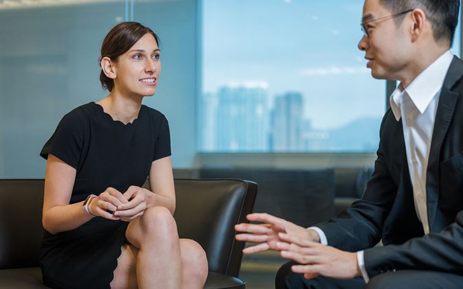 A professional man and woman in conversation in an office setting