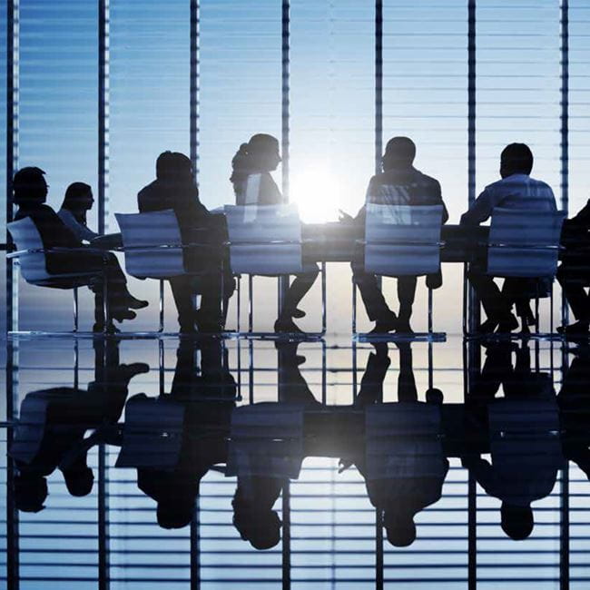 A group of people sitting around a conference table in a modern glass office