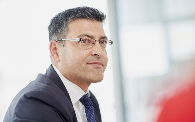 Man with suit and glasses listening to colleague