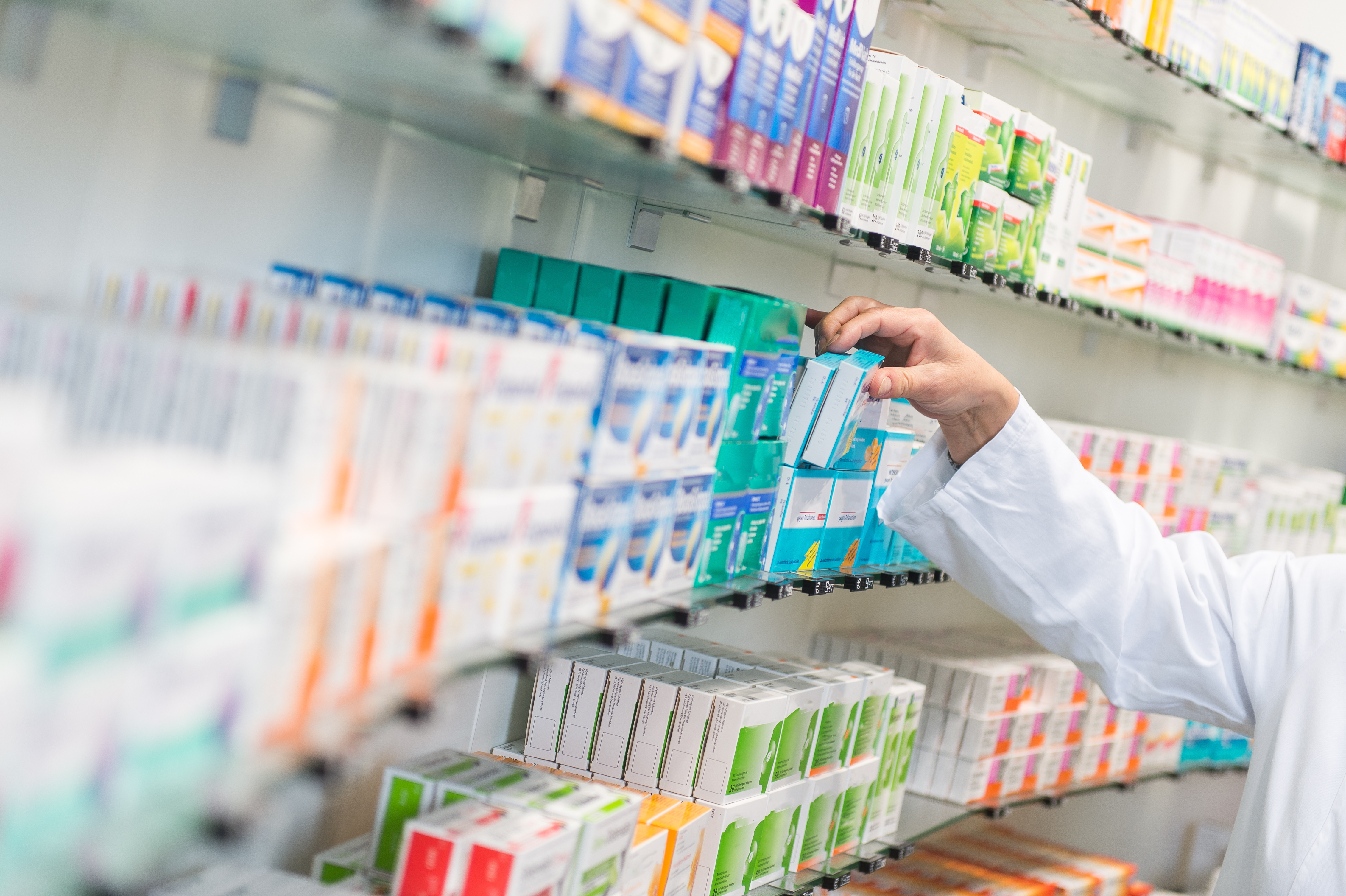 pharmacist lifting medication from a shelf