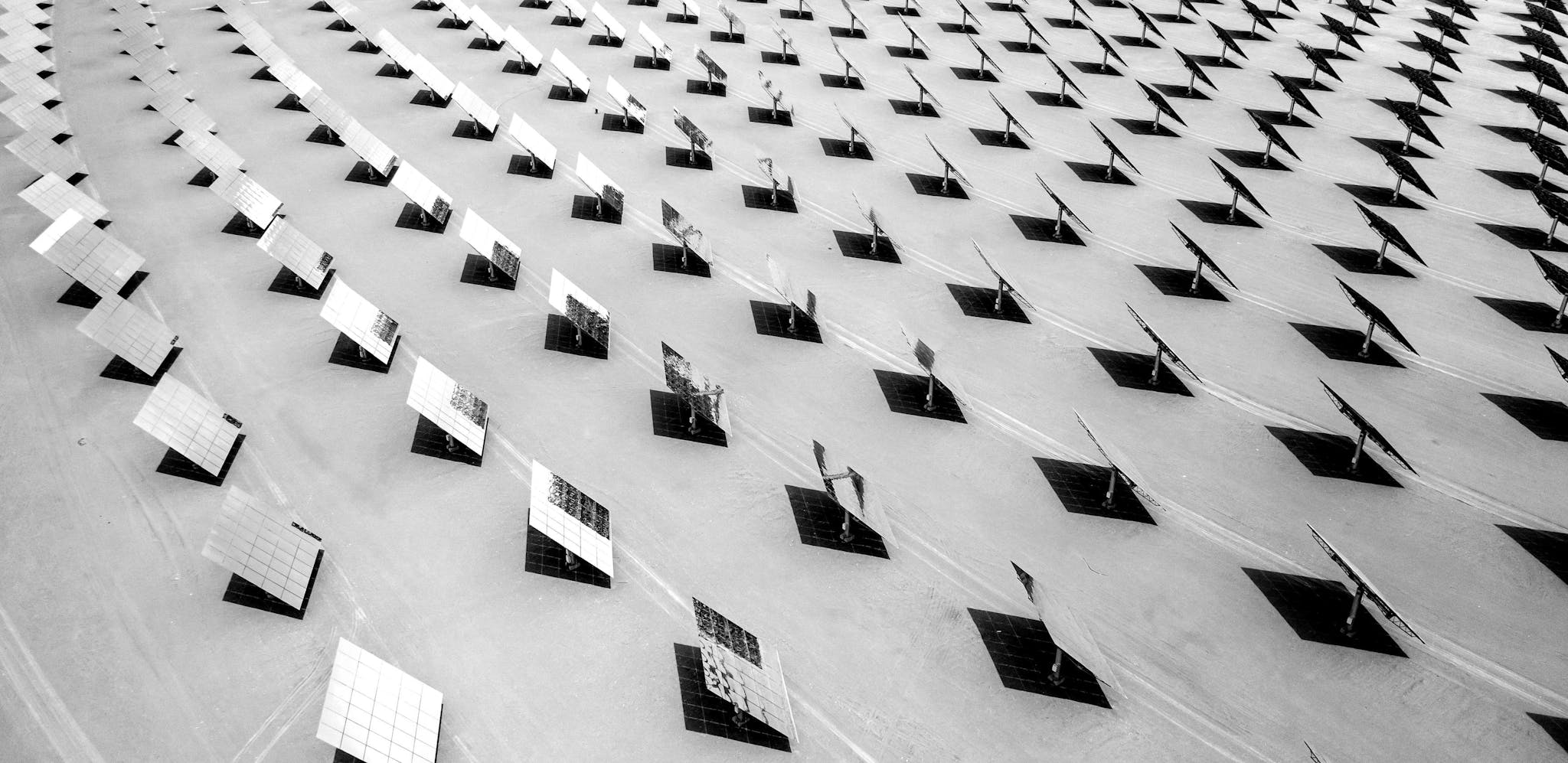 Black and white aerial shot of a circular array of solar panels shining in the sun