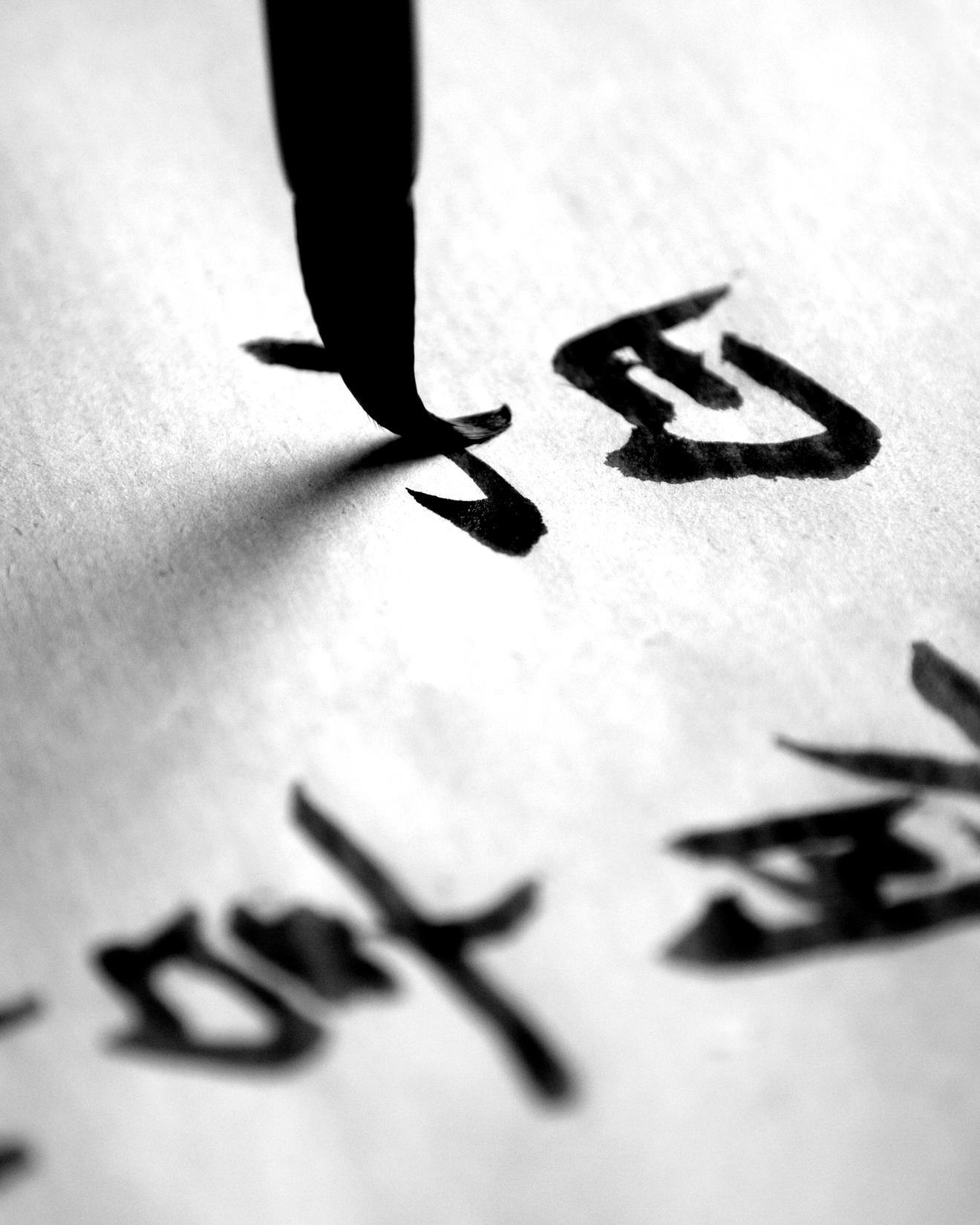 Close up image of Chinese calligraphy characters and quill