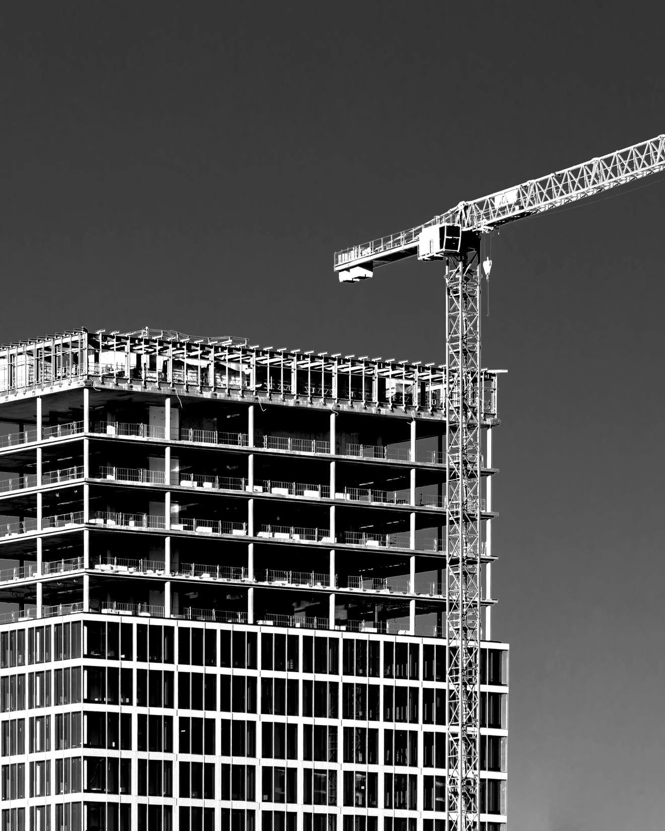 Black and white image of a construction crane in front of a skyscraper being built in Germany
